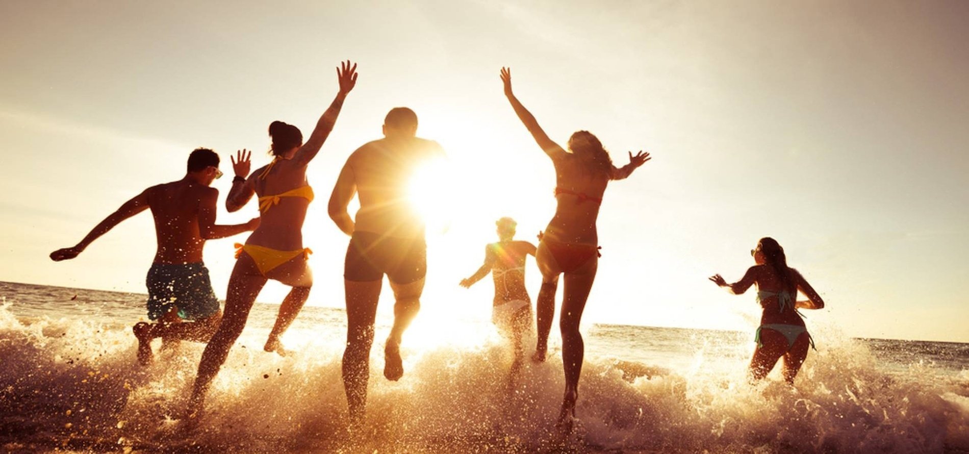 a group of people are running into the ocean at sunset