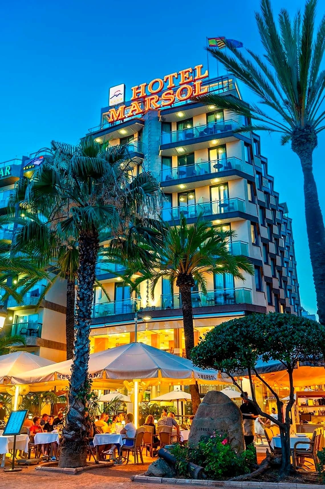 Hotel Marsol en Lloret de Mar: Fachada iluminada y terraza con palmeras.