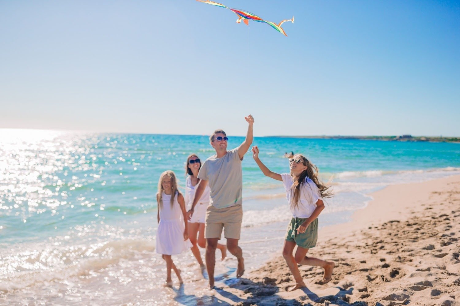 a family is flying a kite on the beach