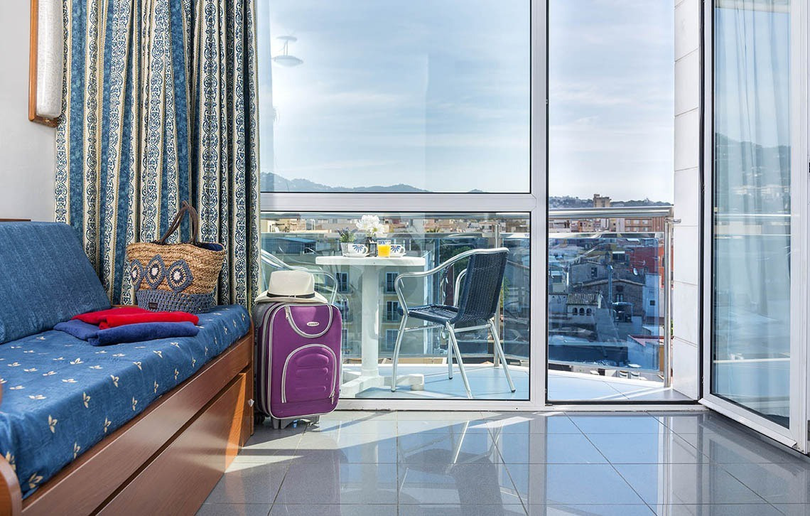 Apartaments Blau a Lloret de Mar: balcó amb vista al mar i maleta, ideal per a la teva estada a Marsol Hotels & Resorts.