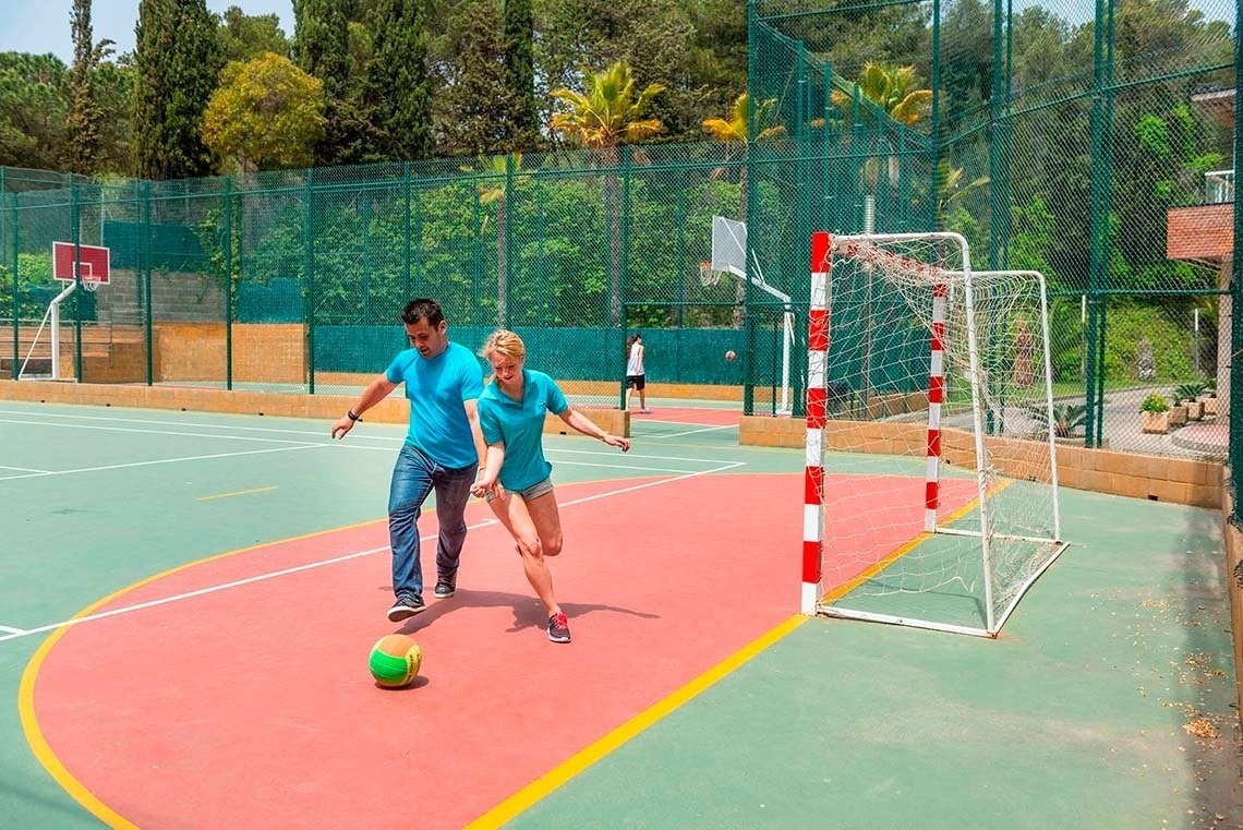 un hombre y una mujer juegan al fútbol en una cancha al aire libre