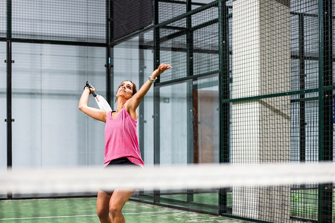 a woman in a pink tank top is playing paddle tennis