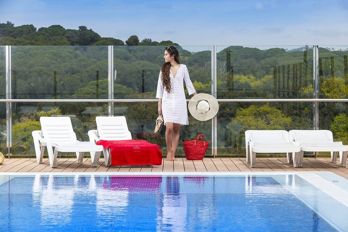 Apartaments Comtat: Dona amb vestit blanc i pamela prop de la piscina del Marsol Hotels.