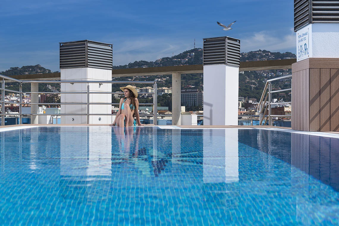 Dona amb barret gaudint de la piscina de la terrassa d'Apartaments Blau a Lloret de Mar | Marsol Hotels & Resorts.