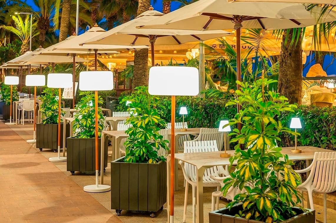 Terraza de verano Hotel Marsol, mesas al aire libre bajo sombrillas, iluminación cálida.