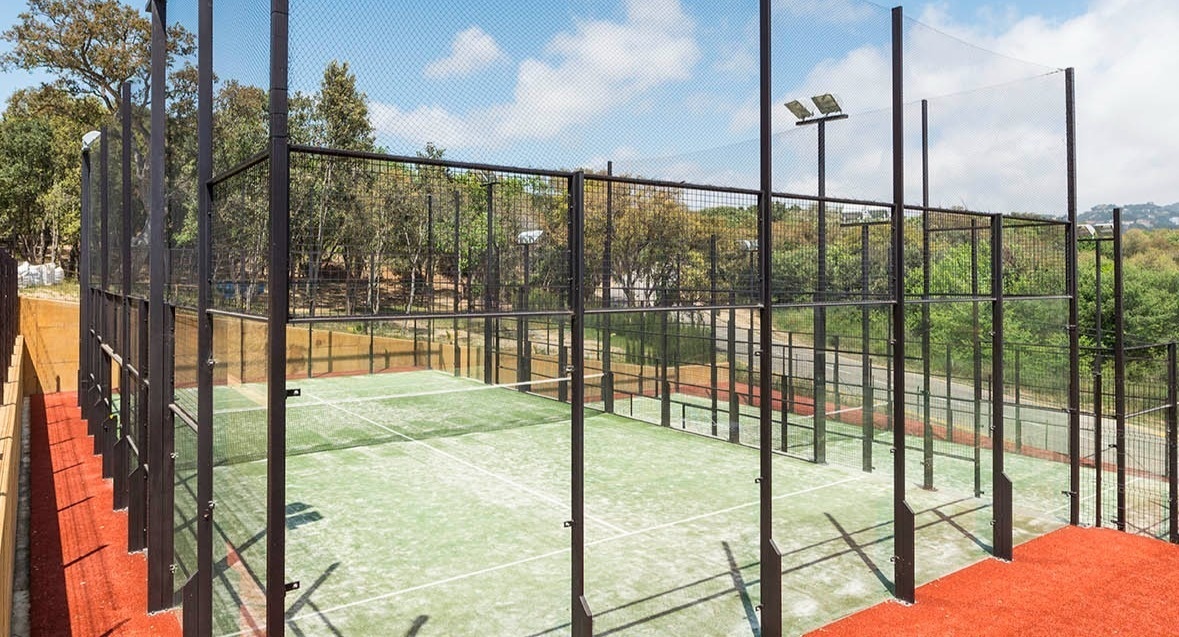 a tennis court with a fence around it and trees in the background