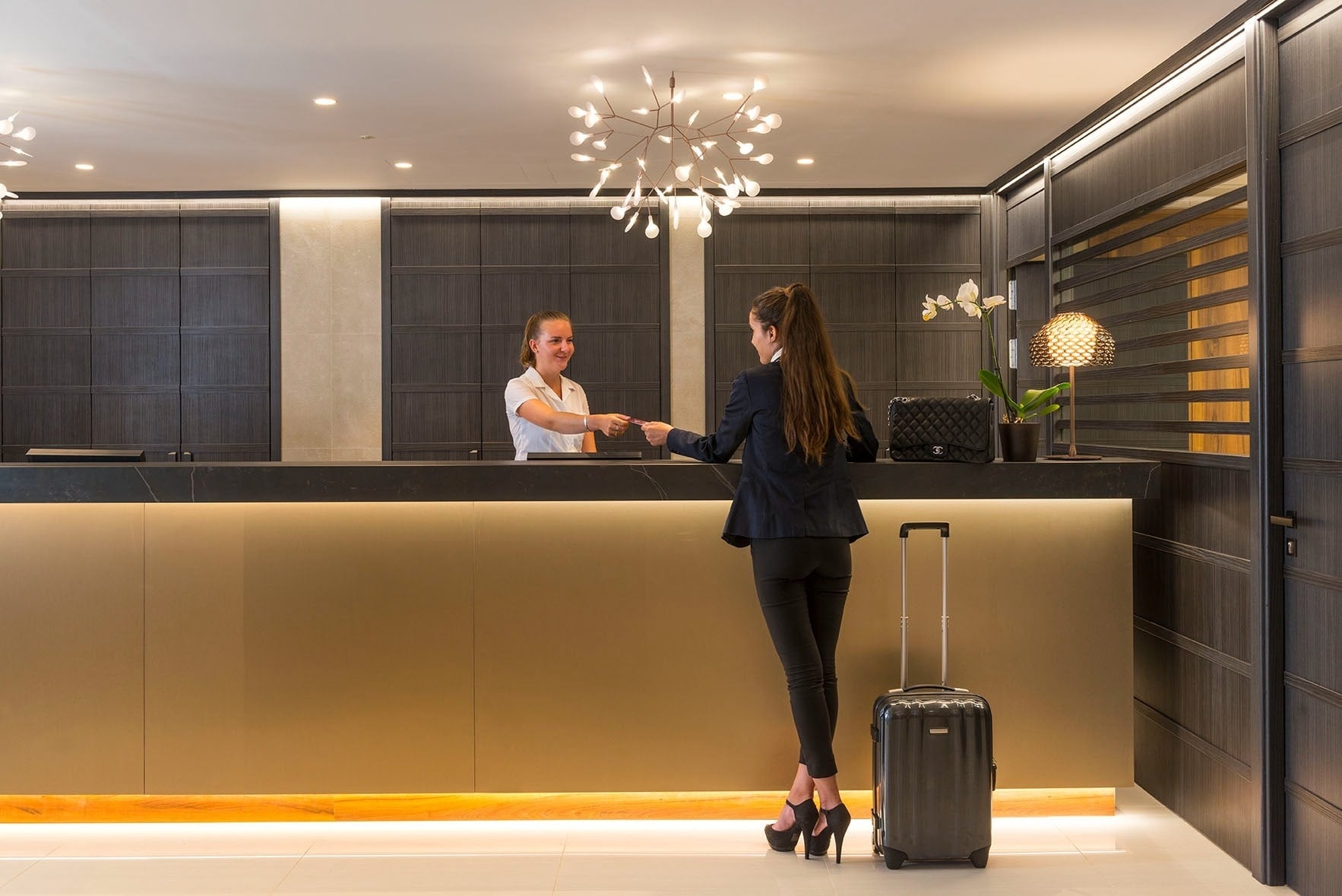 una mujer con una maleta se encuentra en la recepción de un hotel