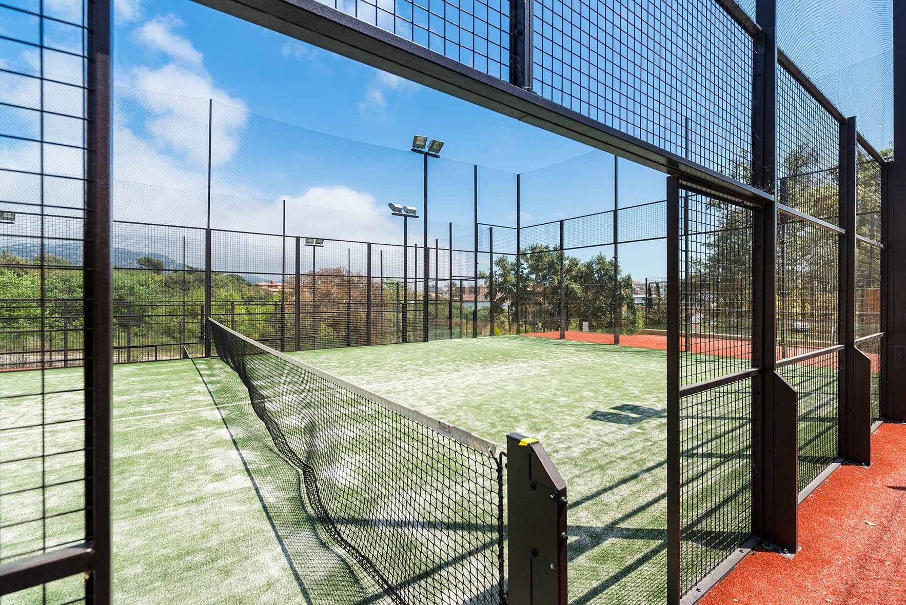 una pista de padel coberta d' una malla de metal