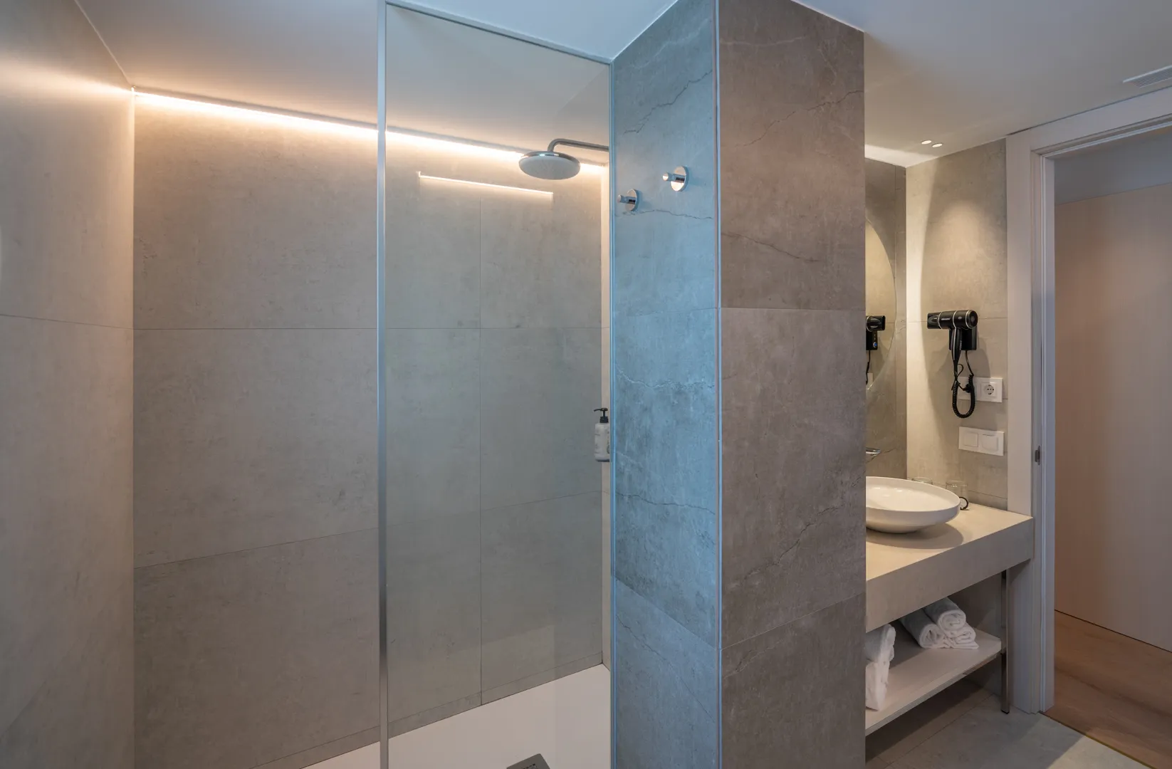 Baño moderno con ducha de cristal, lavabo y secador de pelo. Costa Encantada Suites & Resort en hotel.