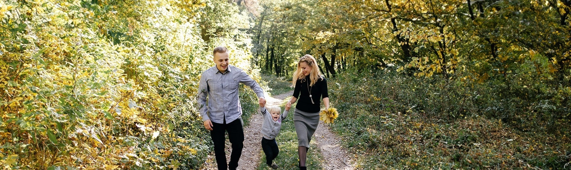 a family is walking through a forest with two children on their shoulders