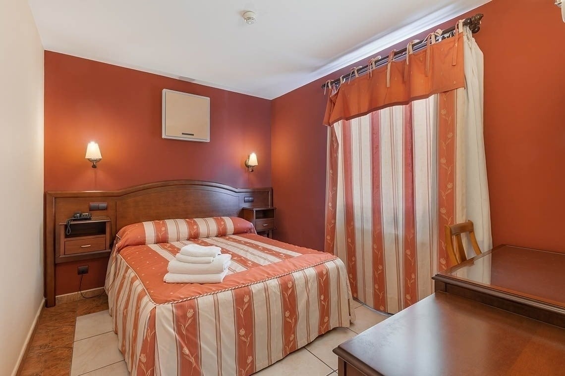 a hotel room with a bed and striped curtains