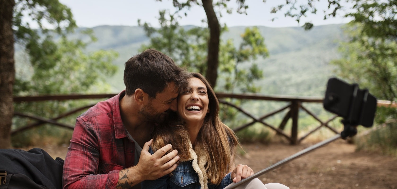 a man kisses a woman on the cheek while taking a selfie