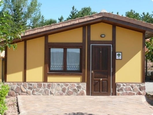 una pequeña casa amarilla con una puerta de madera y una ventana