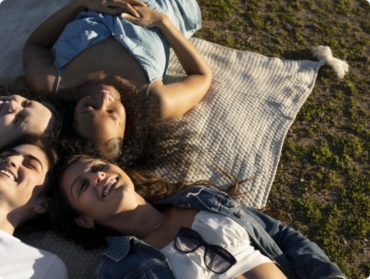 a group of people laying on a blanket in the grass