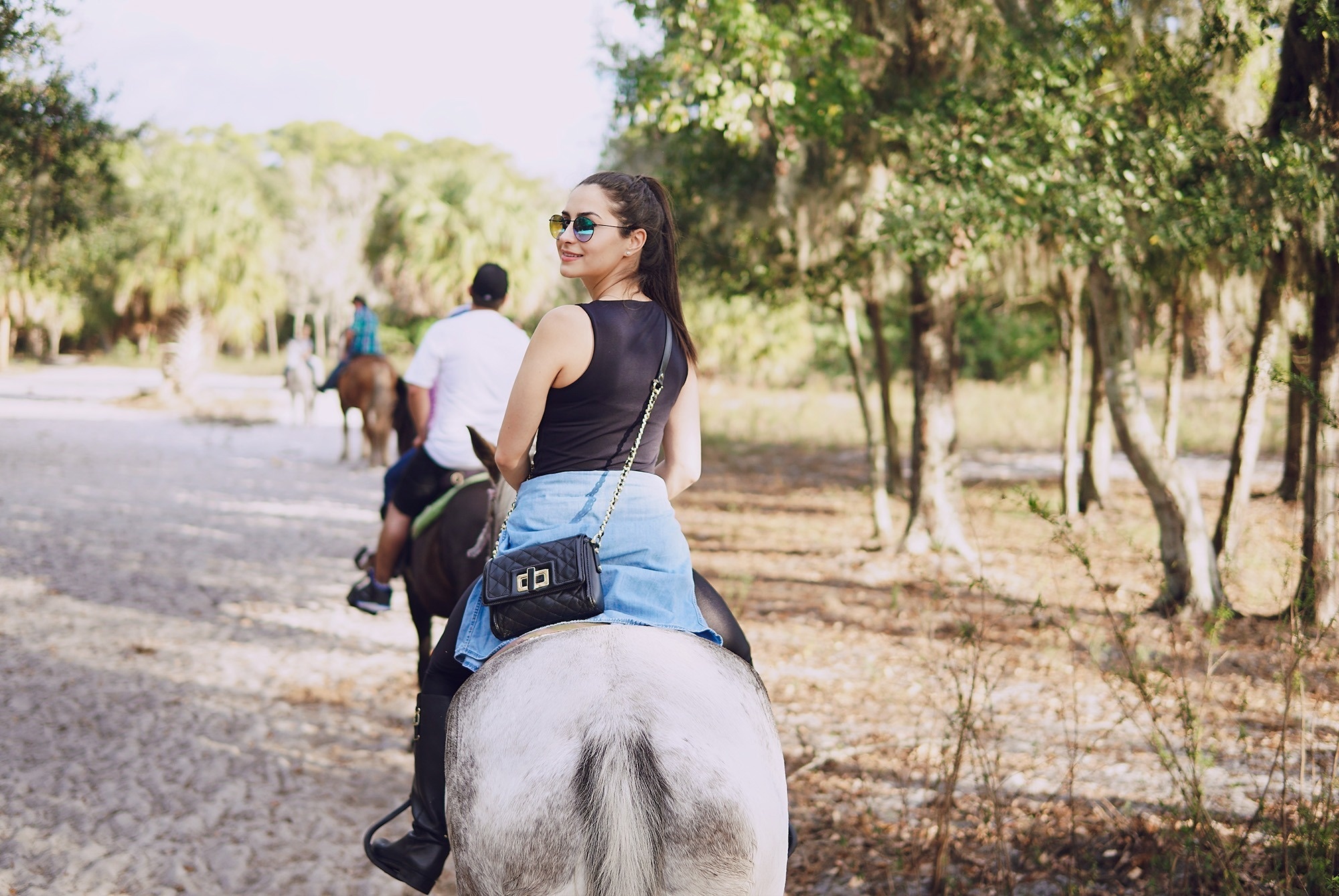 una mujer con gafas de sol monta un caballo en un bosque