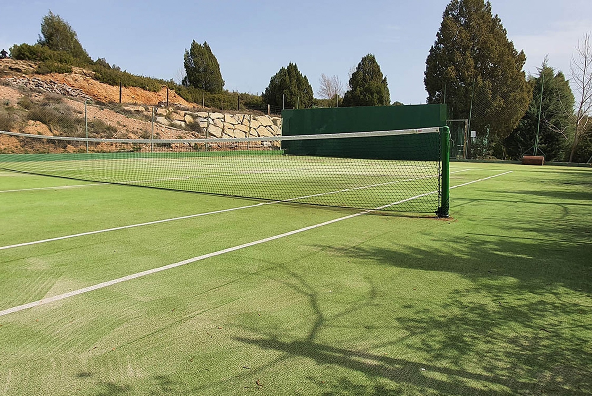 una cancha de tenis con una red y una pared verde