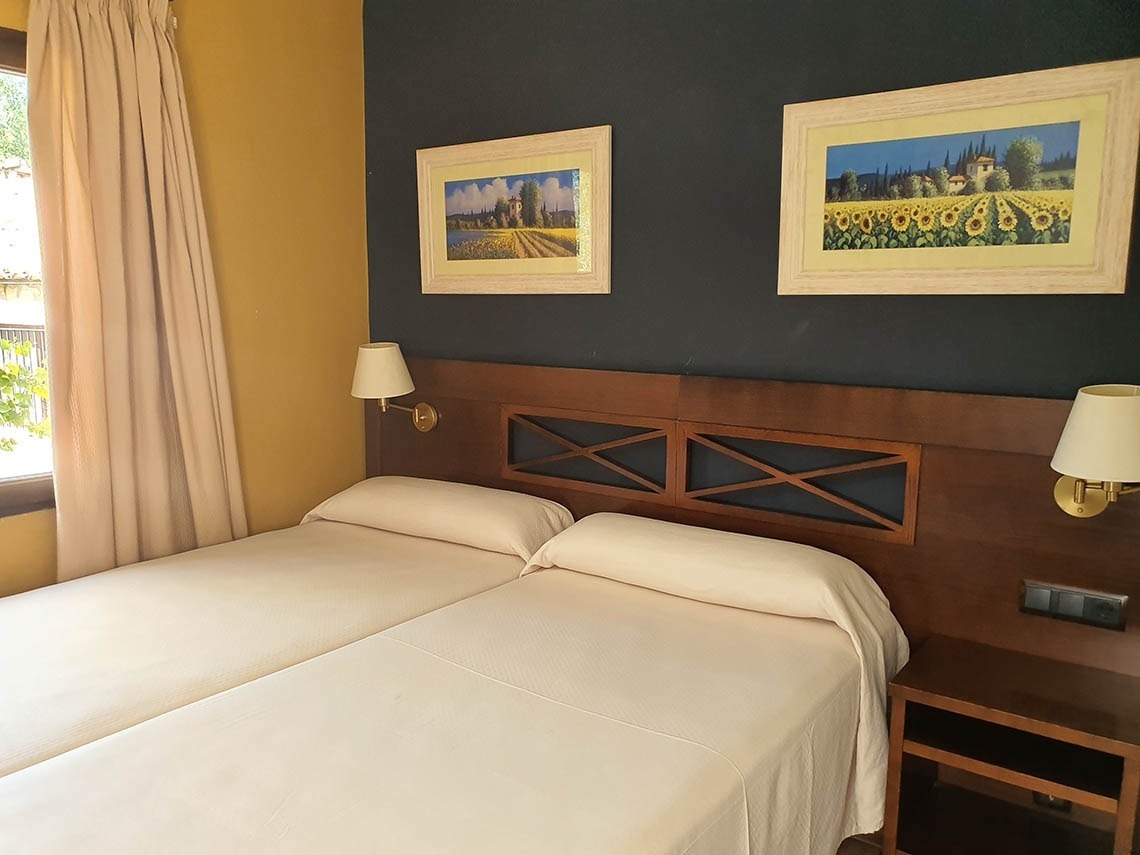 una habitación con dos camas y dos cuadros en la pared