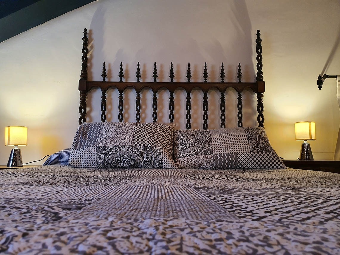 una cama con dos lámparas y una cabecera de madera