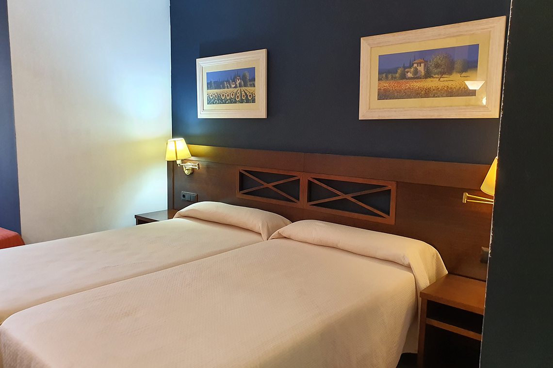 una habitación con dos camas y dos cuadros en la pared