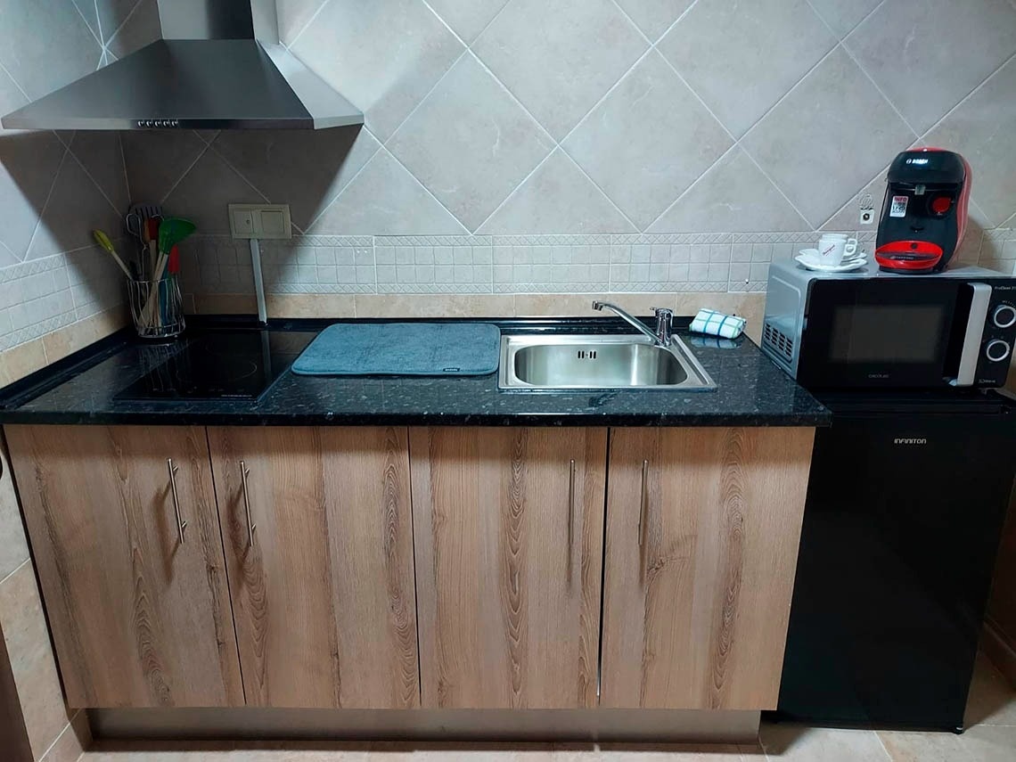 una cocina con gabinetes de madera y una nevera negra