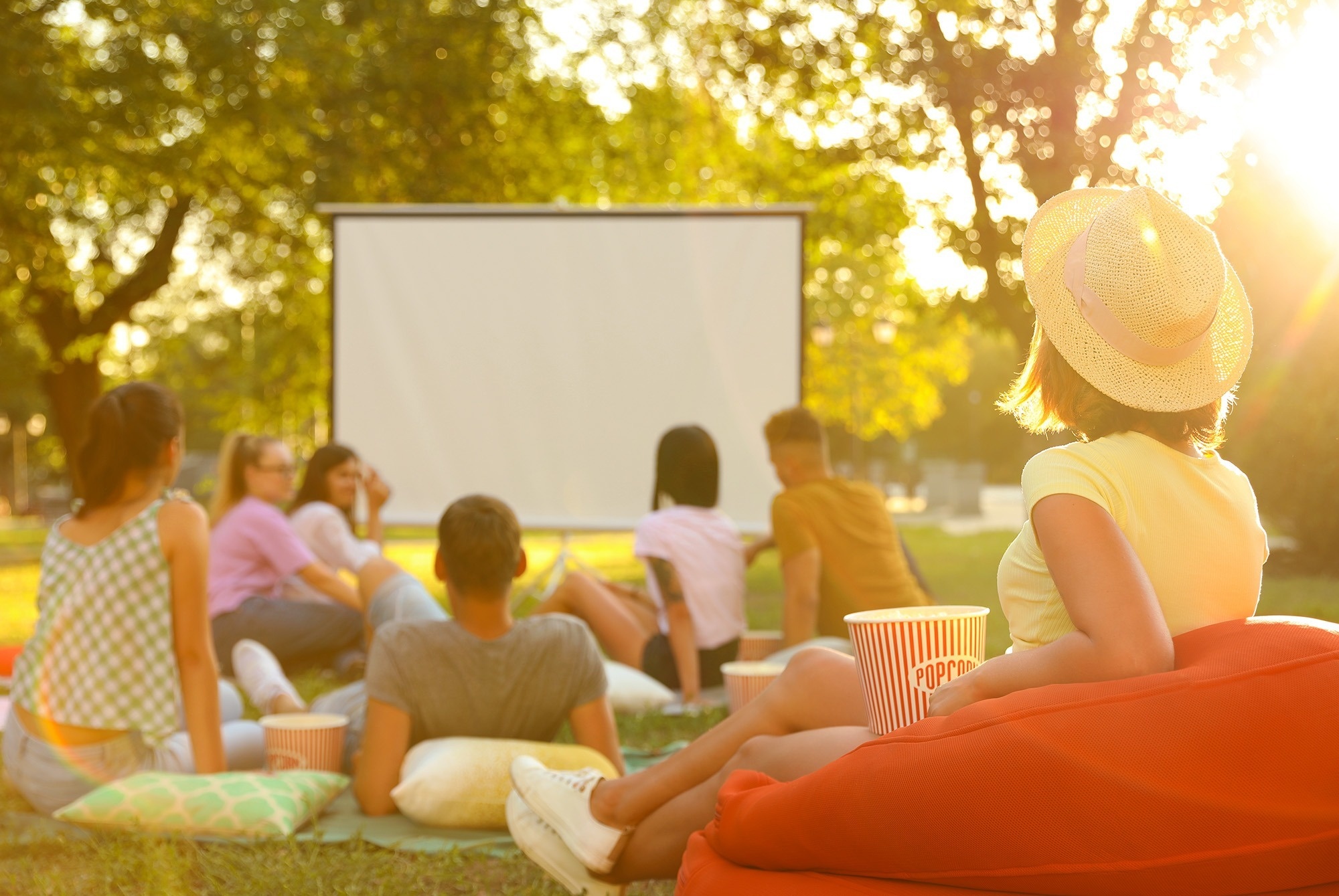 un grupo de personas viendo una película al aire libre con palomitas de maíz