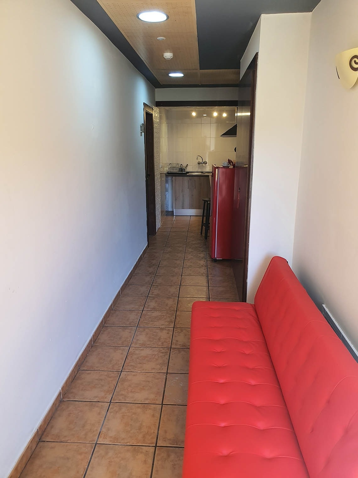 un sofá rojo se sienta en un pasillo junto a una cocina