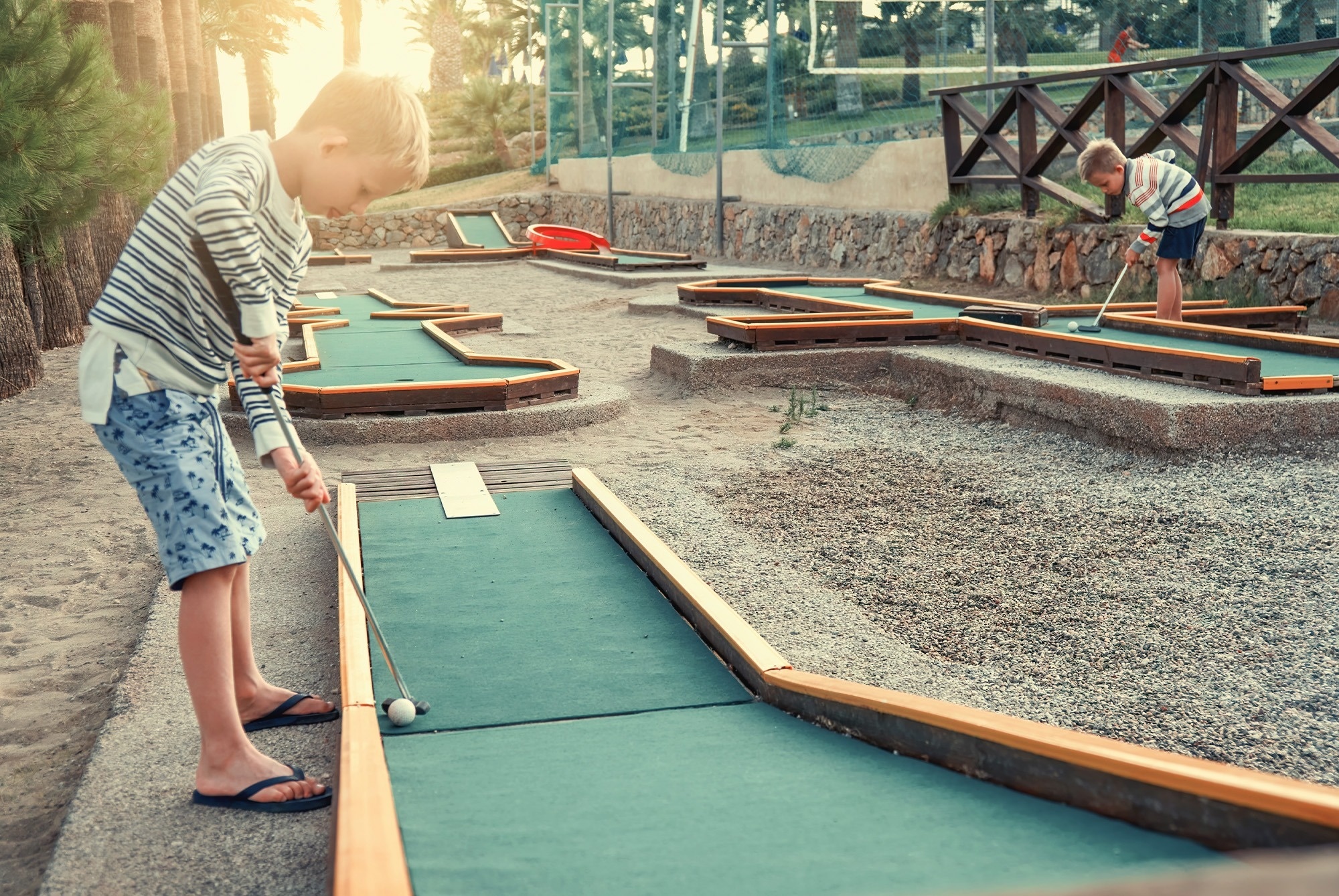 dos niños juegan al minigolf en un parque