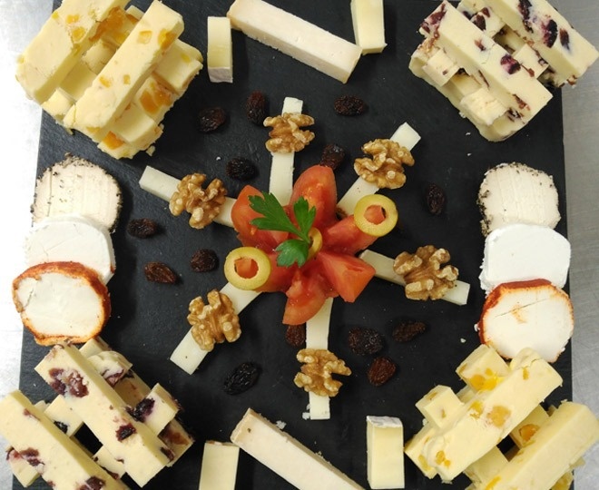 una variedad de quesos , nueces , tomates y pasas están dispuestos en un círculo