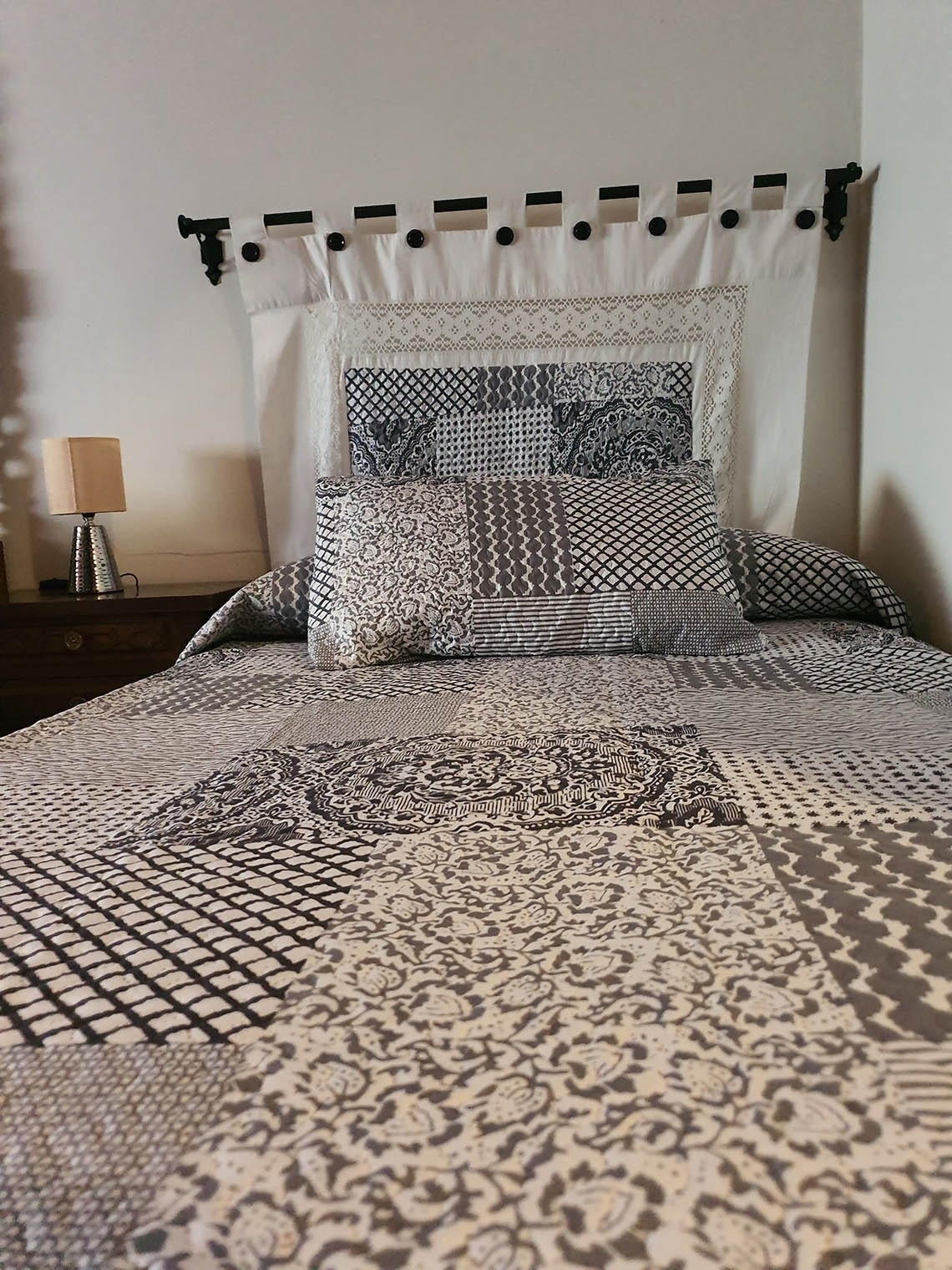 una cama con un edredón gris y blanco y almohadas