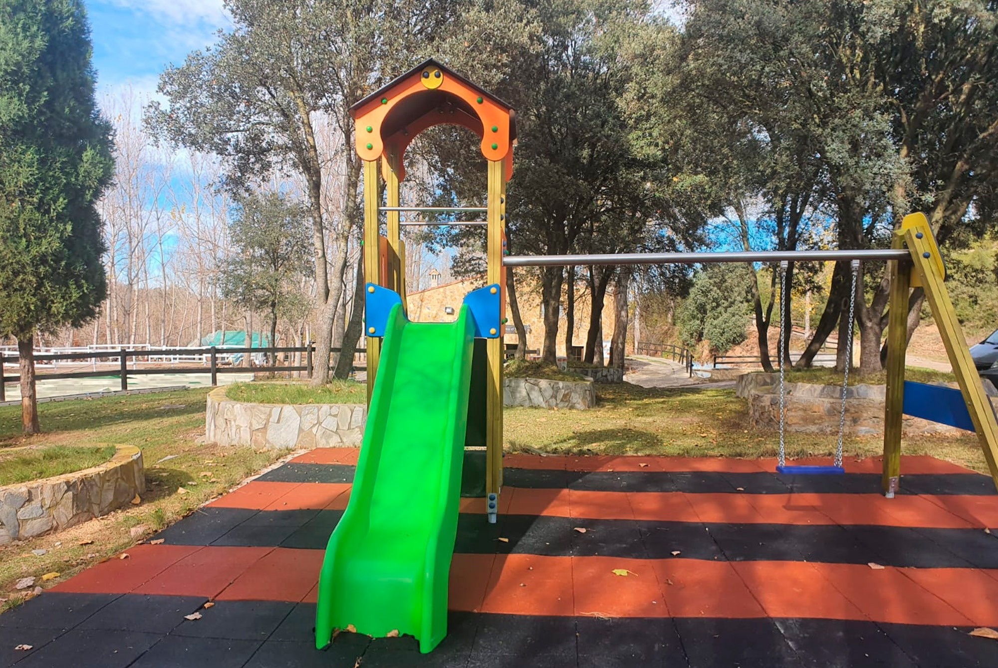 un tobogán verde y un columpio en un parque