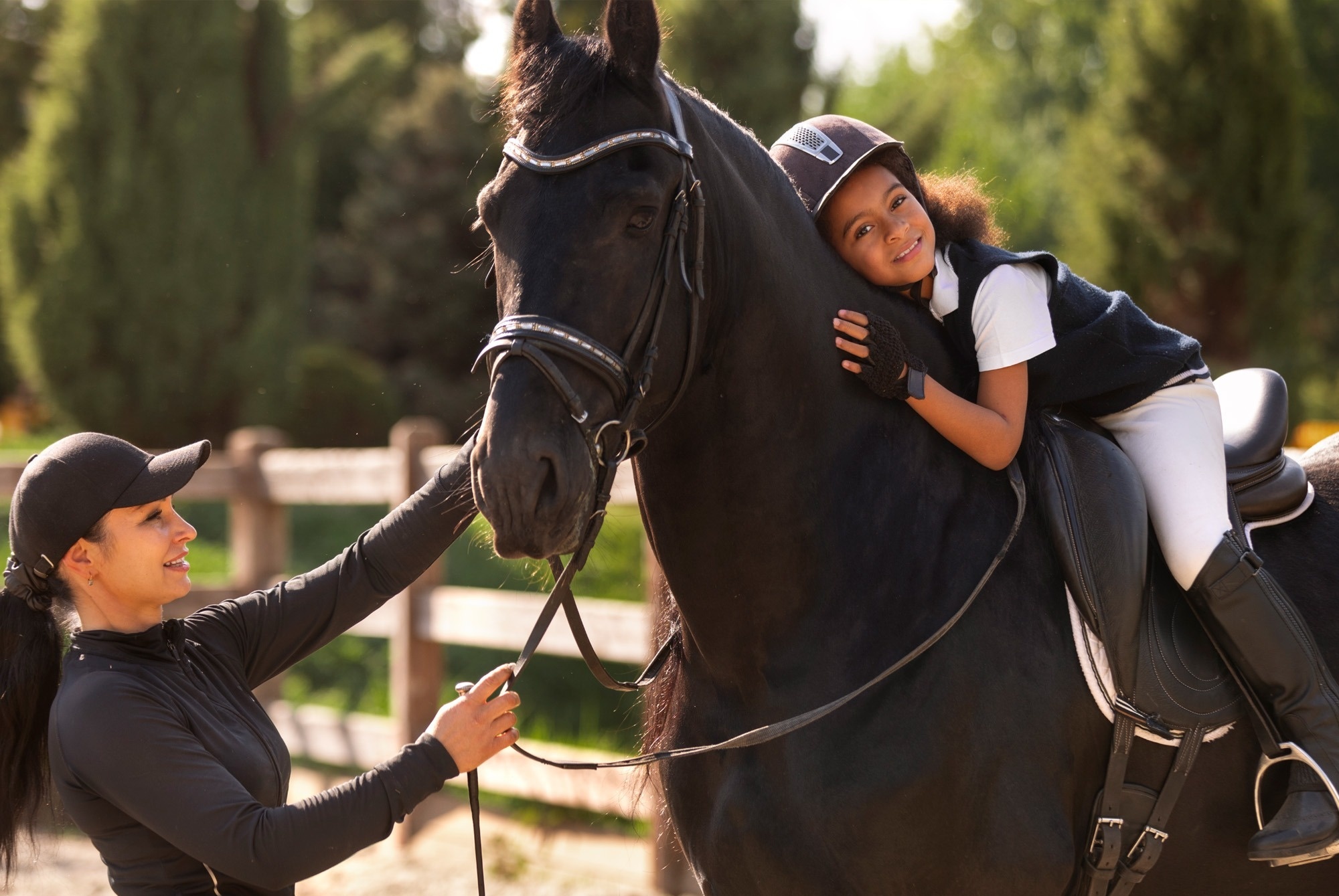 una niña está sentada en un caballo con una mujer a su lado