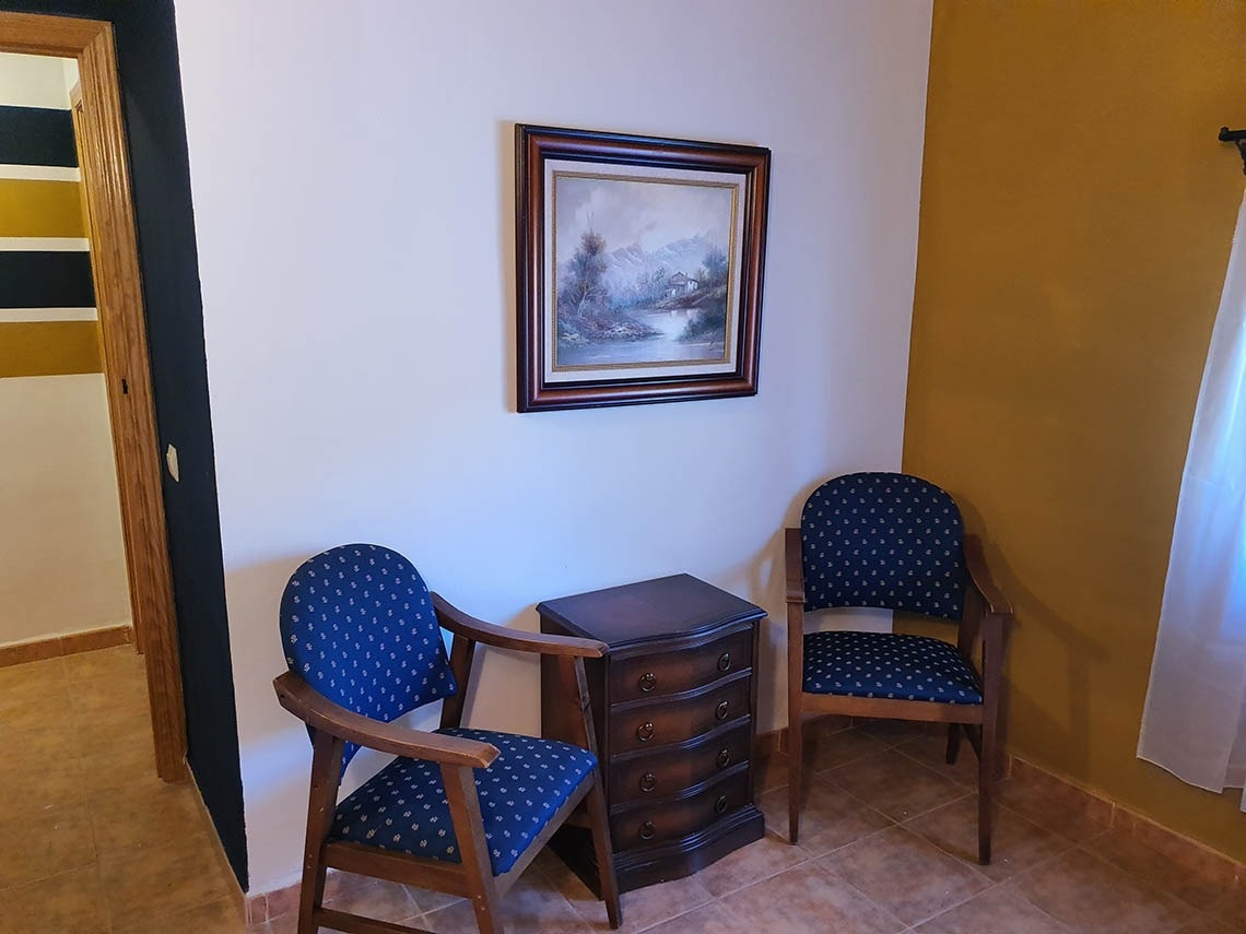 dos sillas y una cómoda en una habitación con una pintura en la pared