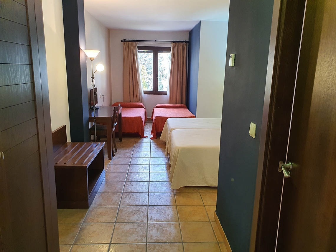 una habitación con tres camas y una mesa