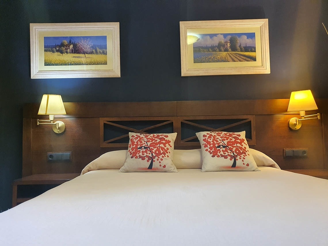 una cama con dos almohadas y dos cuadros en la pared