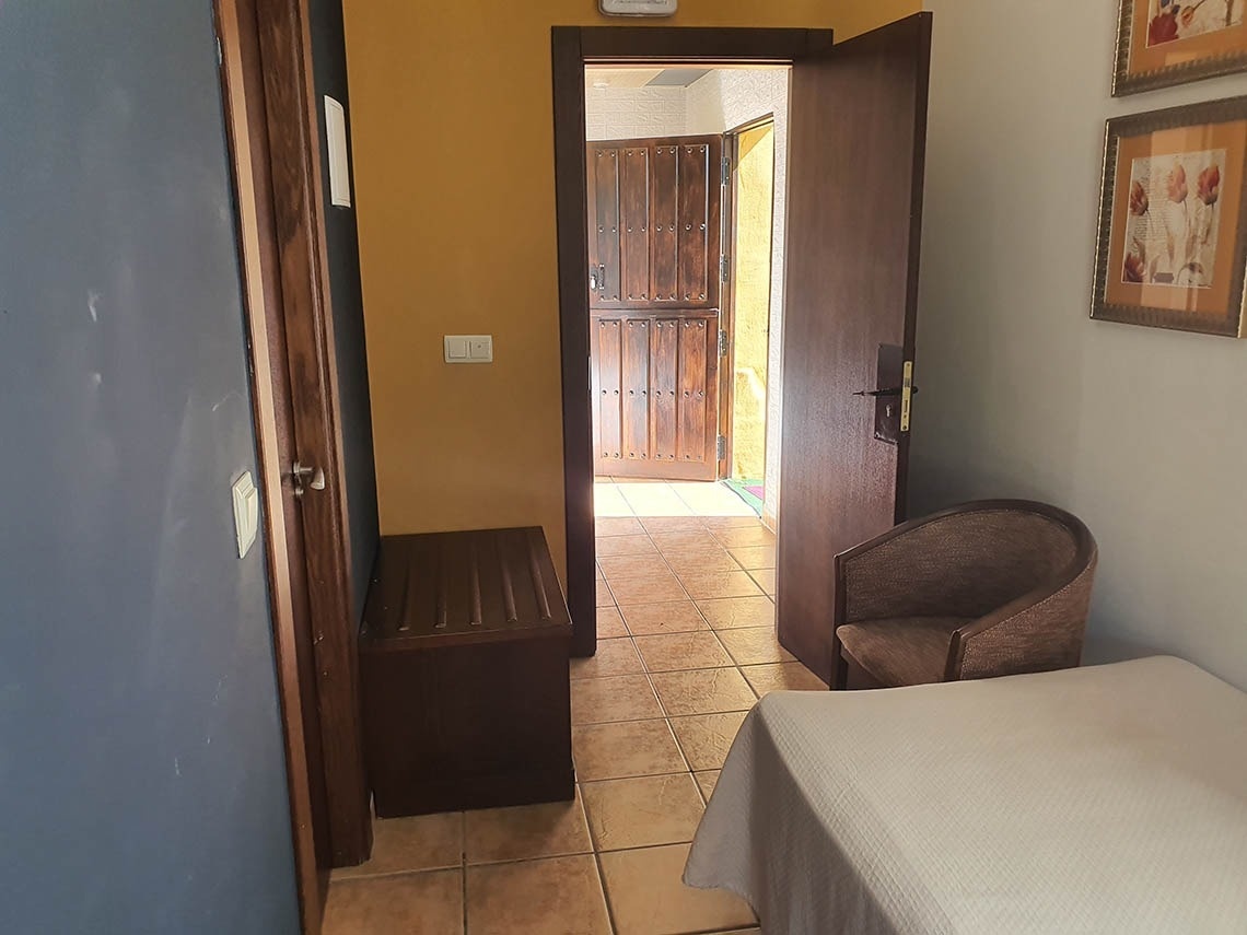 una puerta de madera se abre a una habitación con una cama y una silla