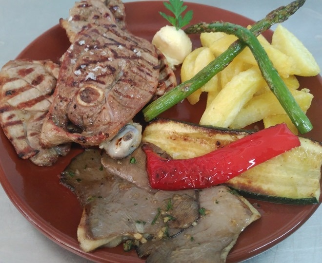 un plato de carne y verduras con papas fritas y espárragos