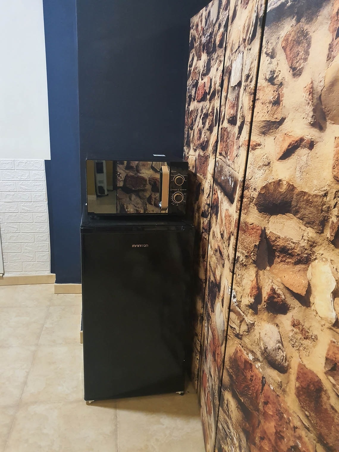 una nevera negra y un microondas están junto a una pared de ladrillos