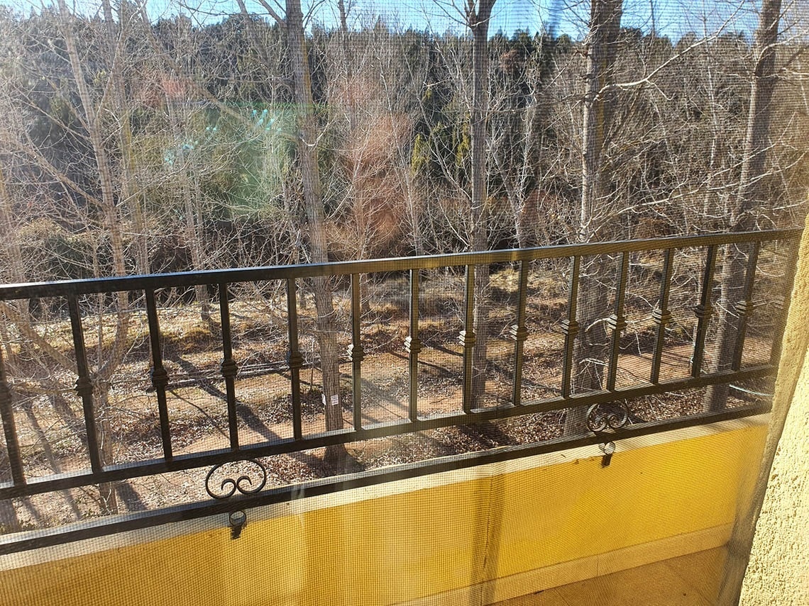 una vista de los árboles desde un balcón con una barandilla de hierro forjado