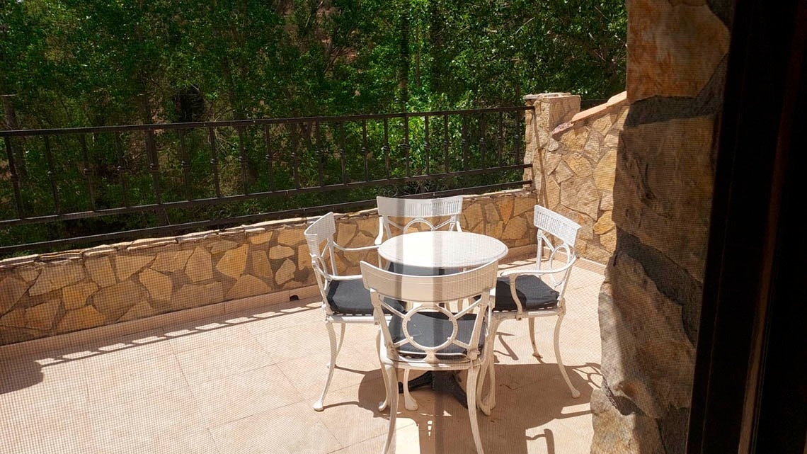 una mesa y sillas en un balcón con una valla de hierro