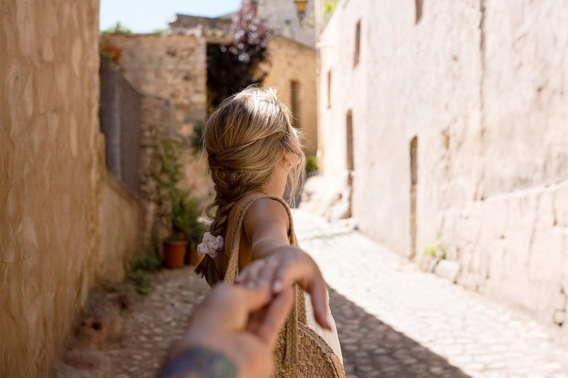 una mujer sostiene la mano de un hombre mientras camina por una calle