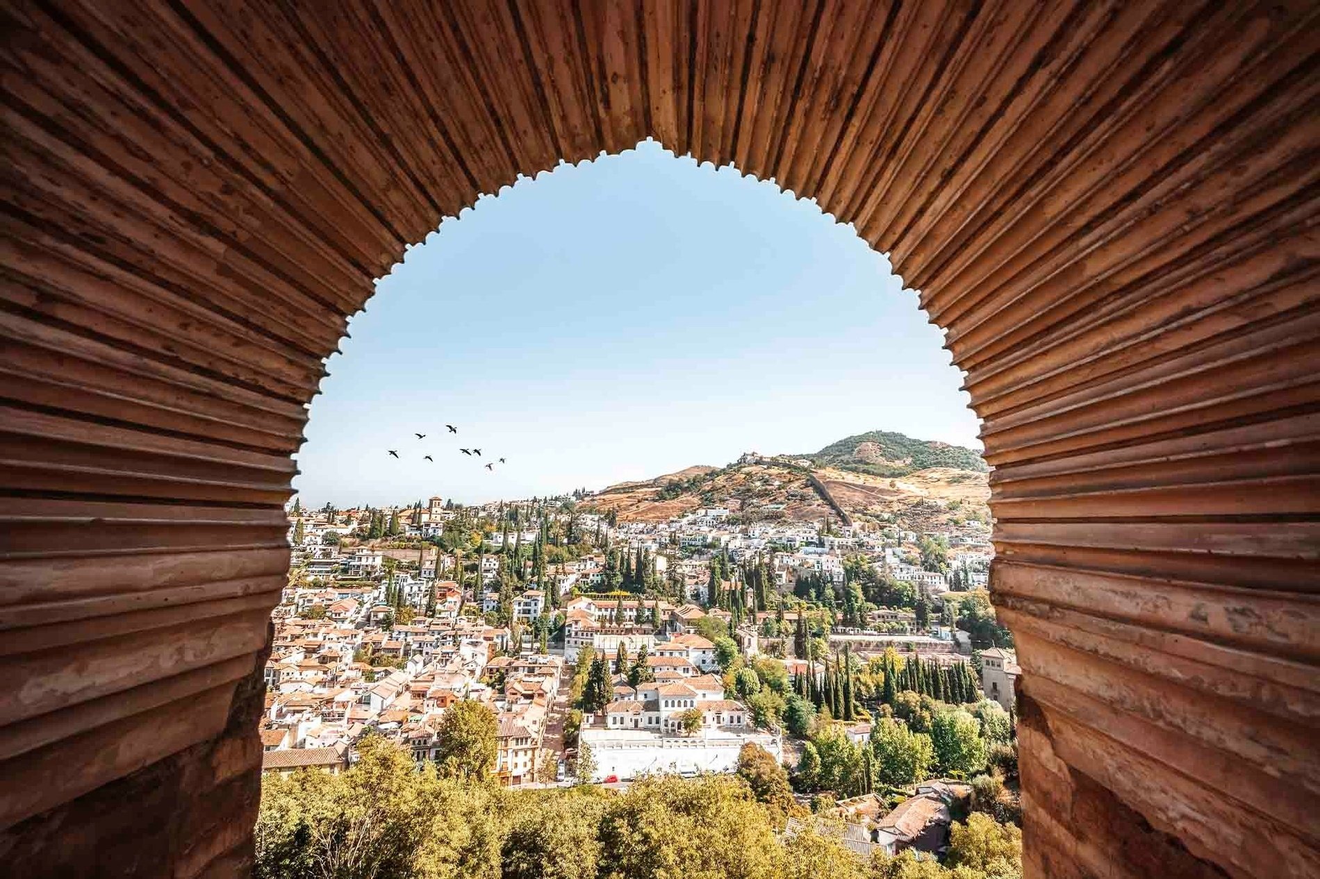 una vista de una ciudad a través de un arco de madera=s1900