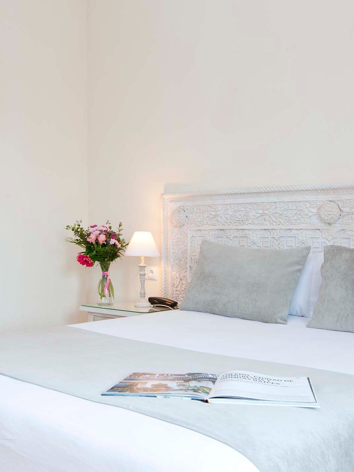 una cama con una revista abierta y un jarrón de flores