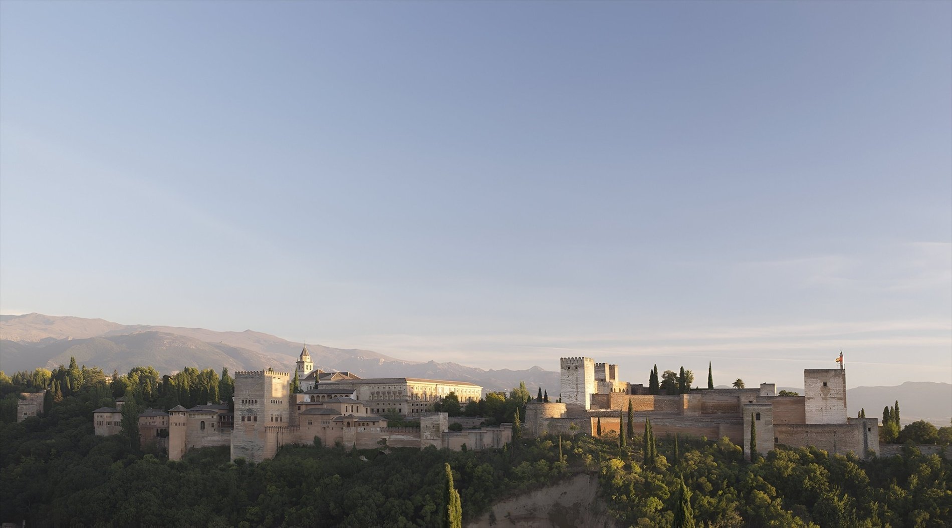un castillo con montañas en el fondo al atardecer