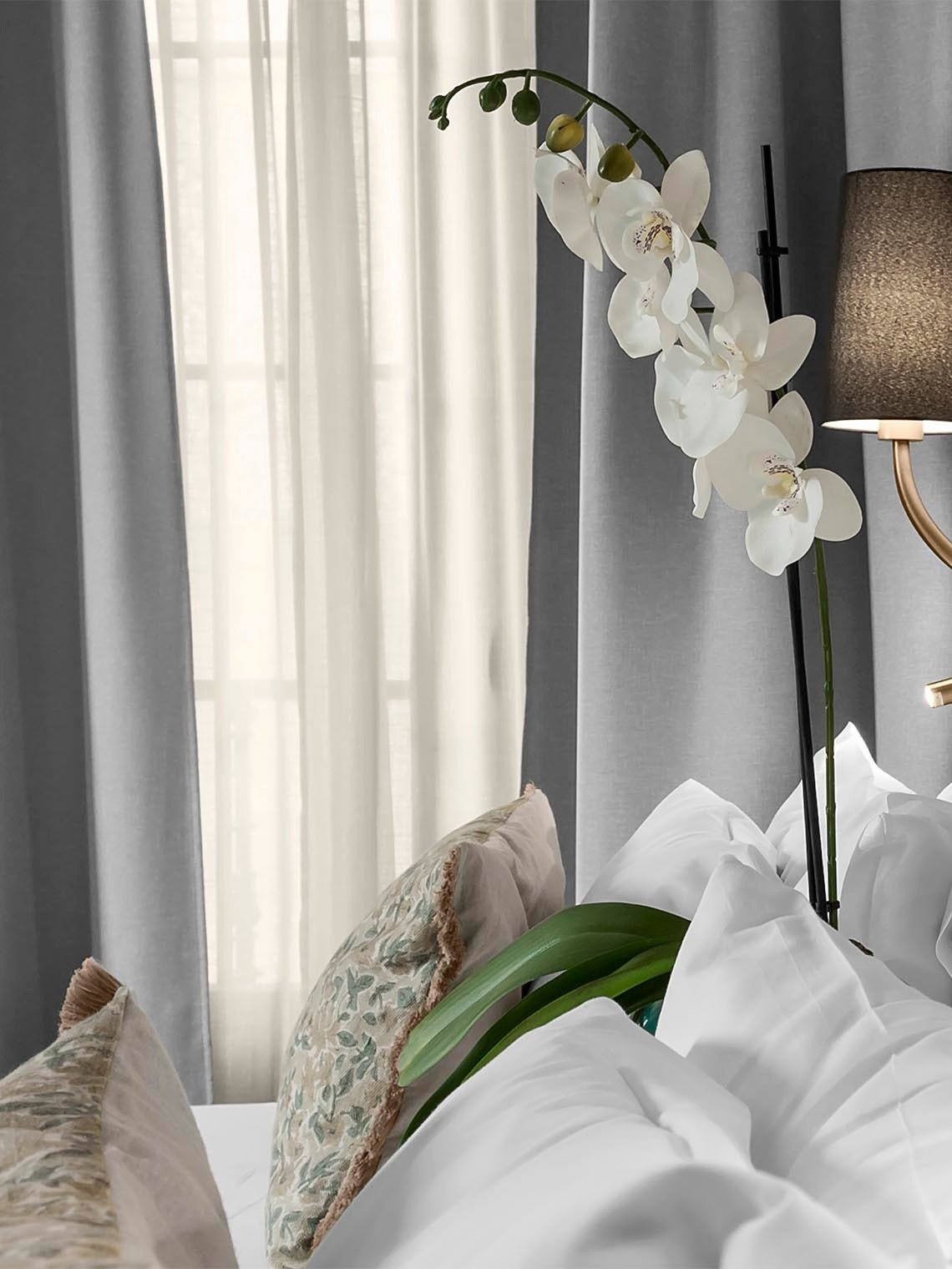 una planta de orquídeas se sienta en una cama junto a una lámpara