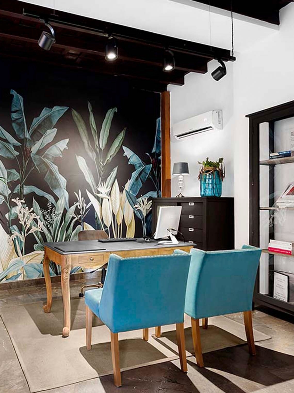 una habitación con una mesa y sillas y un mural de hojas en la pared