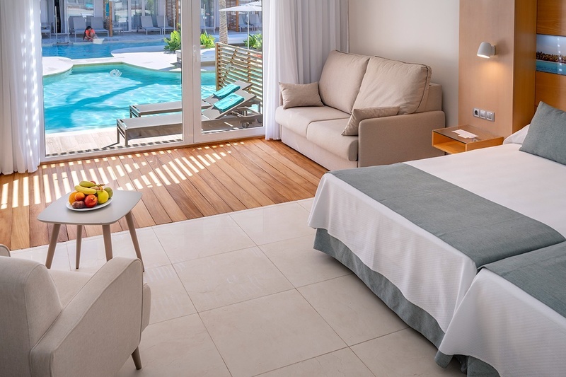 una piscina rodeada de muebles y sombrillas en un hotel