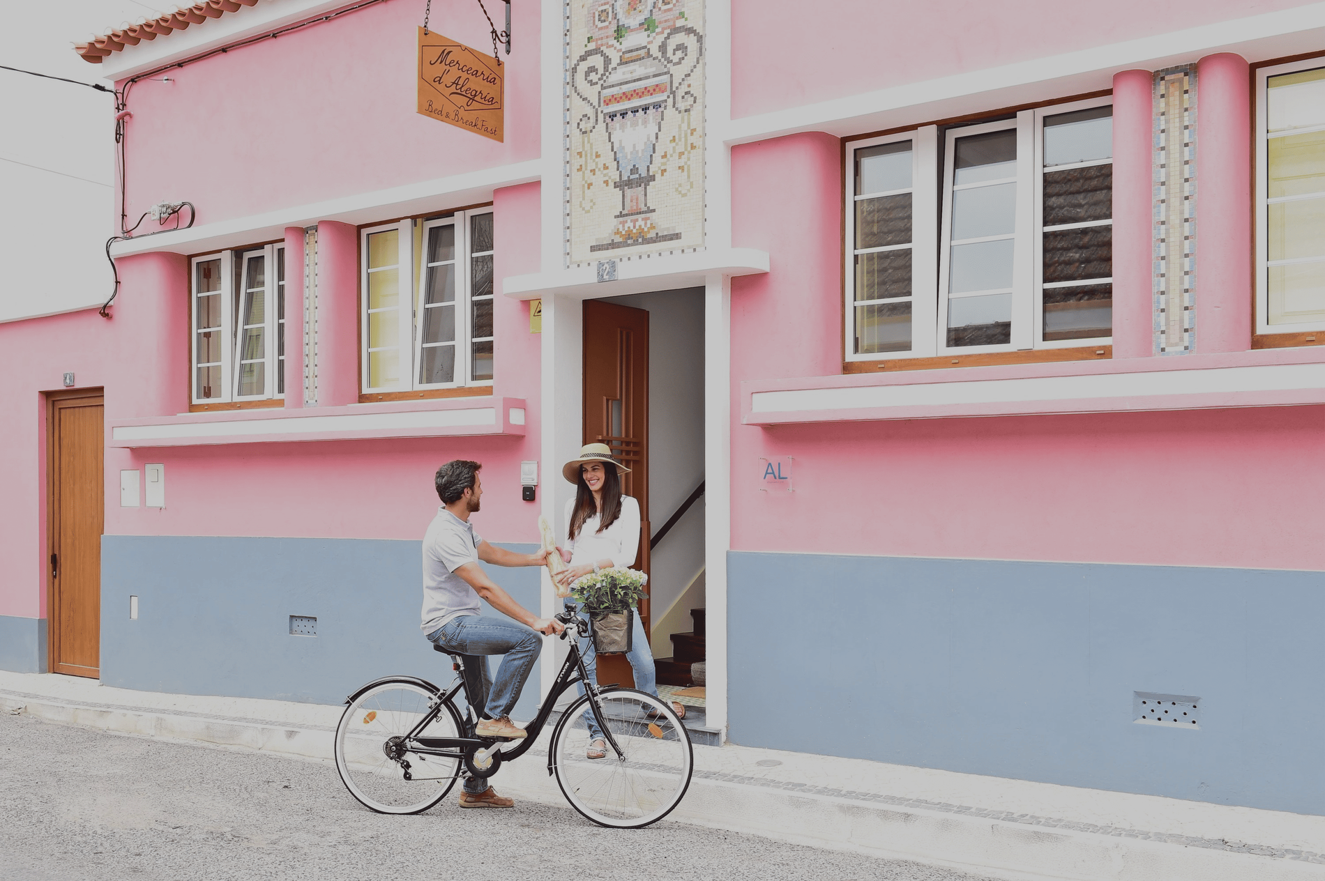 um homem está andando de bicicleta em frente a uma casa rosa