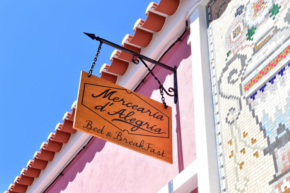 um sinal pendurado na lateral de um prédio diz mercearia d alegria