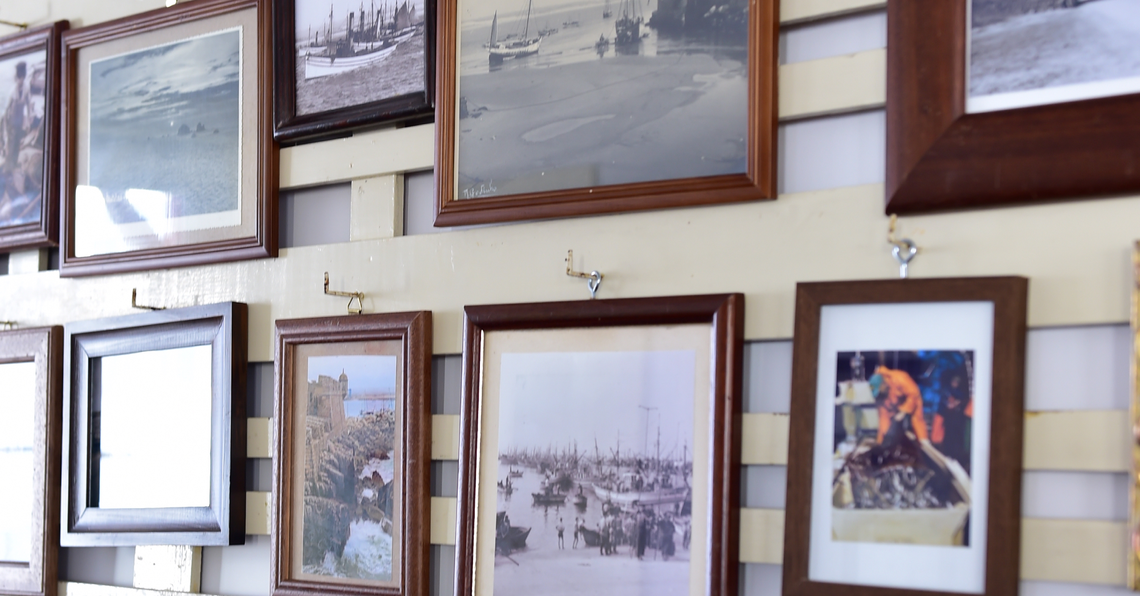 uma parede cheia de quadros de madeira com uma foto de um barco ao fundo