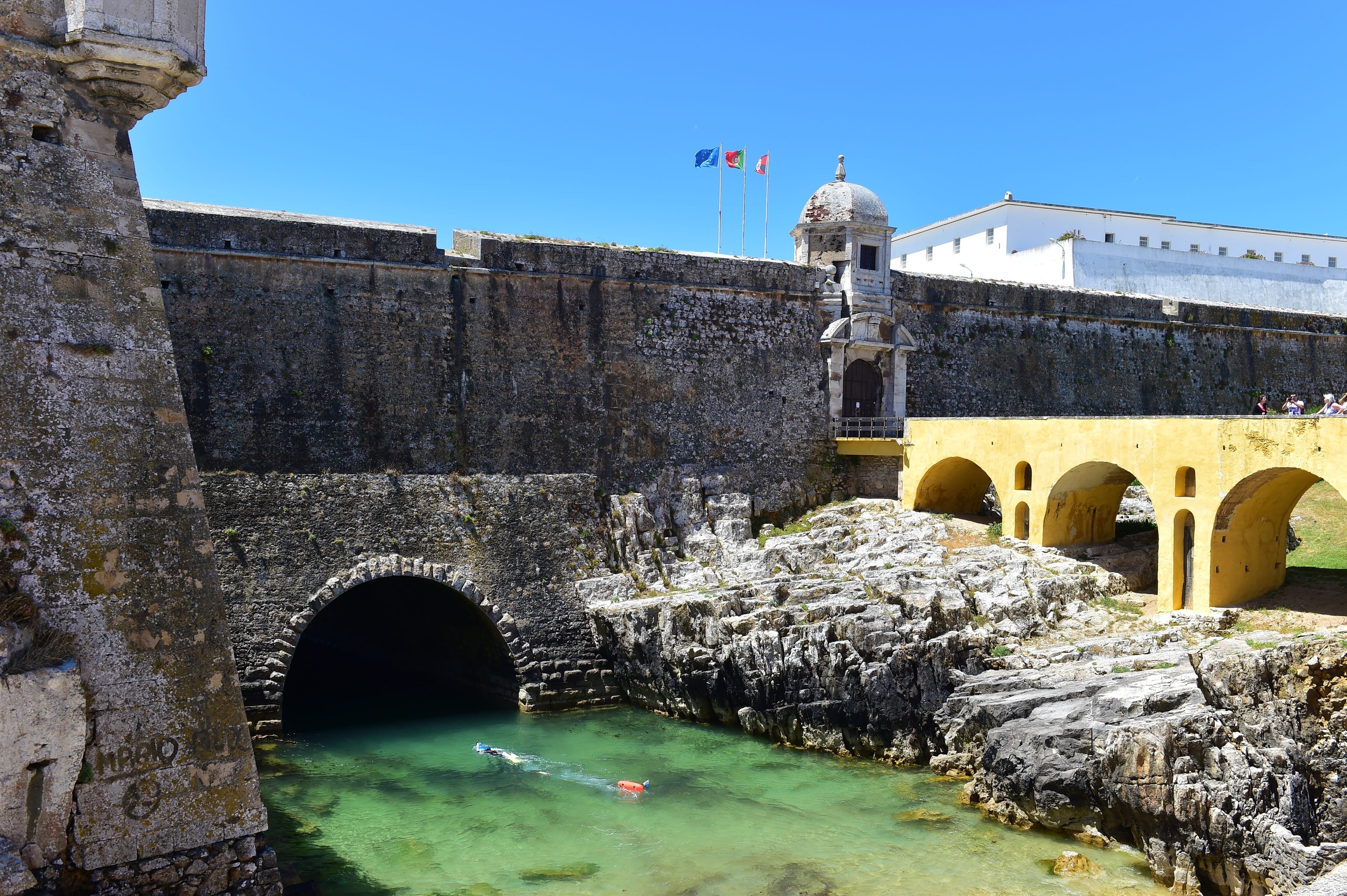 a man is swimming in a pool next to a stone wall .